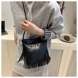Détail d'un sac bandoulière vintage noir avec franges et texture en daim élégante