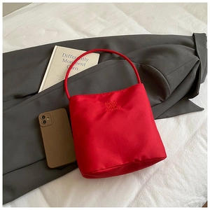 Détail du sac seau en toile rouge avec broderie Hope and Future sur un fond texturé