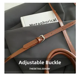 Detail of adjustable brown leather strap with silver metal buckle on a retro tote bag
