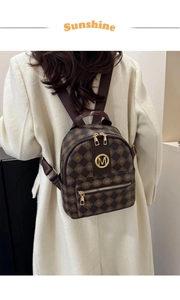 Détail d'un mini sac à dos à carreaux café avec logo M doré porté sur un manteau beige