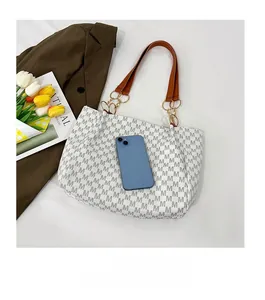 Detailed size comparison of a large tote bag with a smartphone and monogram print