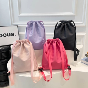 Lightweight drawstring backpacks in four pastel colors on a minimalist display stand