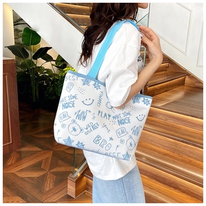 Detail of white canvas tote bag featuring blue doodle prints and casual shoulder straps