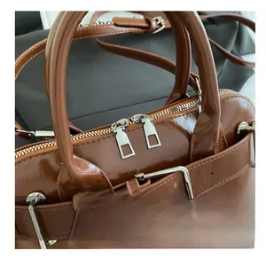 Detail view of smooth brown PU leather shell bag with sturdy metal zipper and buckle