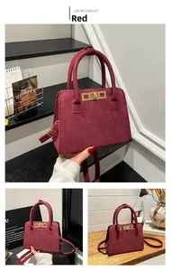Detailed view of red suede handbag with golden metal clasp and adjustable shoulder strap