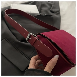 Detail of burgundy velvet underarm bag with silver buckle strap and retro texture