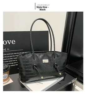 Détail d'un sac cabas noir à texture crocodile avec élégante plaque métallique