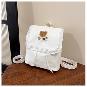 Detail of white leather backpack with lace trim and cute brown bear embroidery