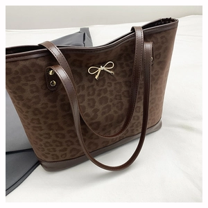 Detailed close-up of brown leopard print tote bag with golden butterfly pendant