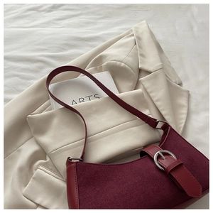 Vue détaillée du sac porté épaule bordeaux en daim avec boucle argentée sur blazer
