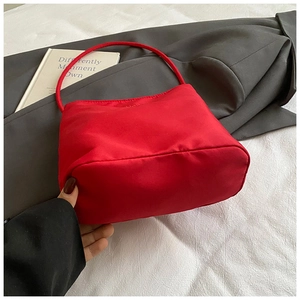 Détail du sac hobo en nylon rouge sur un blazer gris pour une esthétique de mode moderne
