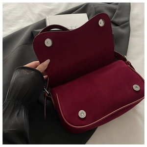 Close-up of matte burgundy suede handbag with silver magnetic snap button closure