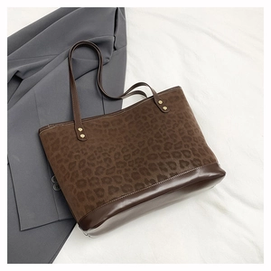 Macro shot of large leopard print tote bag with brown leather trim and golden rivets