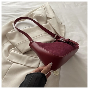 Détail du sac à bandoulière bordeaux avec mélange de textures sur un blazer beige