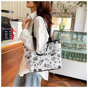 Detail of white tote bag featuring black graffiti bear prints and wide shoulder strap