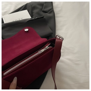 Detail view of the silver metal zipper and dark red leather interior of the minimalist bag