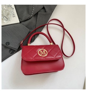 Close-up of red quilted crossbody bag with golden M logo and elegant leather texture