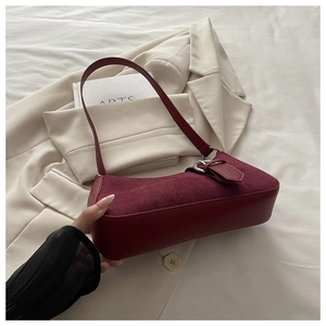 Détail du sac à bandoulière bordeaux avec texture en daim et grande boucle en anneau argenté