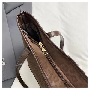 Detail shot of leopard print tote bag with brown leather handles and gold zipper closure