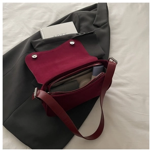 Macro shot of burgundy shoulder bag interior showing compartments and suede texture