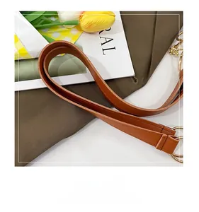 Close-up of brown leather handle with gold chain and detailed stitching on tote bag