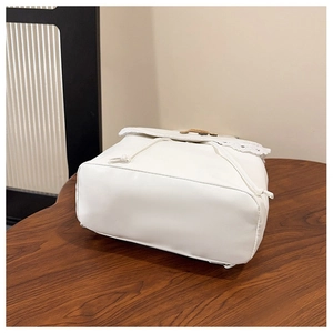Detail of white faux leather backpack featuring decorative lace edges and drawstring closure
