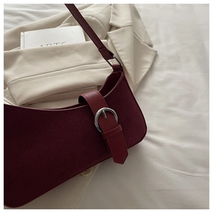 Détail du sac sous le bras en daim bordeaux avec boucle argentée ronde et lanière en cuir