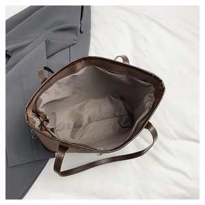 Detailed view of dark brown tote bag interior featuring fabric lining and zipper closure