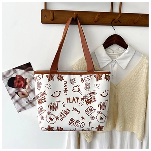 Detail of cream tote bag with brown doodle prints hanging in a cozy lifestyle setting