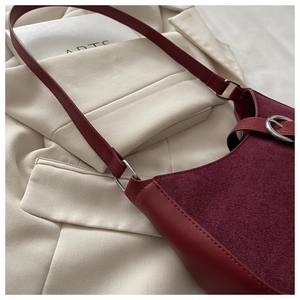 Détail du sac bandoulière bordeaux en cuir avec boucle argentée sur tissu