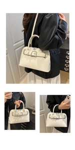 Detail view of stylish cream white handbag with belt buckle and metallic zipper closure