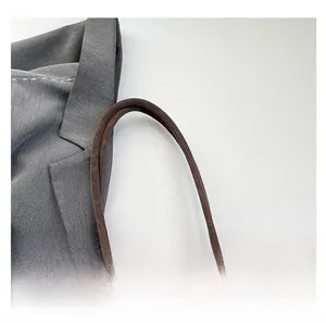 Detail view of smooth dark brown suede tote bag handles with braided knot accents