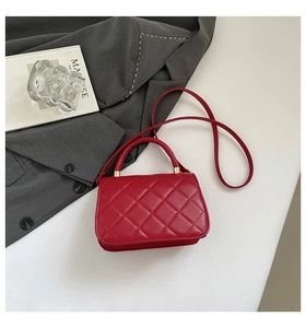 Detail of red quilted faux leather handbag with gold hardware and rhombic pattern