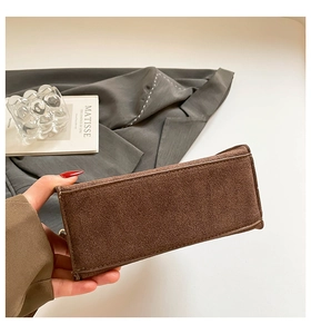 Detail shot of the rectangular bottom of the dark brown matte handbag with fine stitching