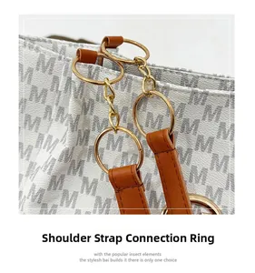 Detail of golden metal rings connecting the brown leather strap to the letter printed tote bag
