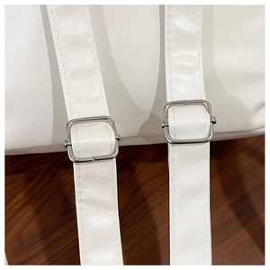 Detail of adjustable white leather straps with silver buckles on a commuter backpack