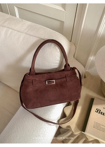 Detail of vintage burgundy faux suede tote bag with silver hardware on a cozy sofa