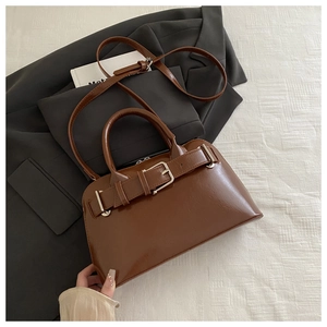 Detail of caramel brown handbag with buckle decor and adjustable strap on a blazer