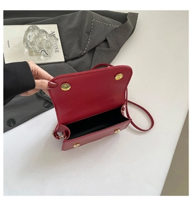 Top view of red flap bag with golden dual magnetic closures and black interior lining