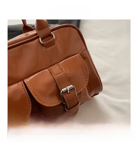 Dettaglio borsa bowling marrone lucida con tasche vintage e fibbie metalliche