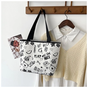 Detail of canvas tote bag with black graffiti prints and durable black handles on hook