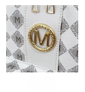 Detailaufnahme des goldenen M-Logos auf hochwertigem weißem Leder mit Litchi-Prägung