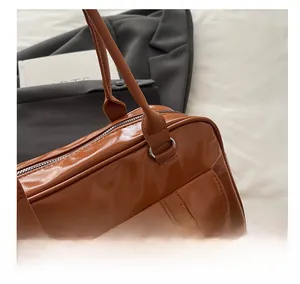 Dettaglio della borsa in pelle marrone lucida con fibbie argentate e tasca laterale a patta