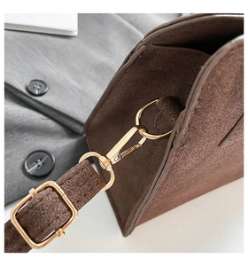 Detailed close-up of brown suede bag with gold-tone hardware hooks and adjustable strap