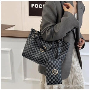 Detail of the large black M-pattern tote bag with matching pouch shown on a model