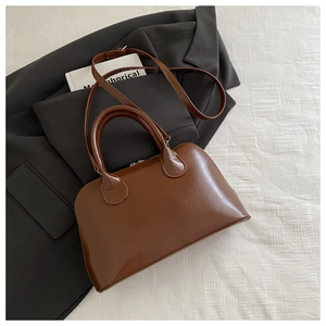 Detail of a brown vintage Boston bag placed on a grey suit for a professional commute look