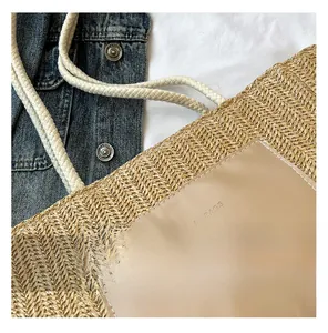Close-up of woven straw tote bag with leather logo patch and cotton rope handle