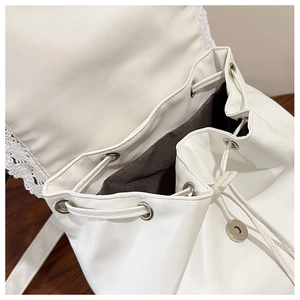 Close-up of white PU backpack featuring delicate lace trim and drawstring closure detail