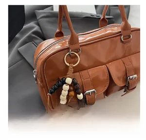 Dettaglio borsa Boston in pelle PU marrone con tasche vintage e ciondolo in perline di legno