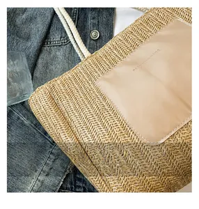 Detail of woven tote bag featuring a leather patch and white cotton rope handles